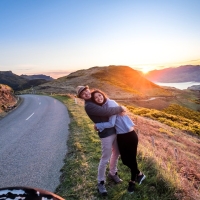 couple hugging on summit road with Akaroa Harbor in background